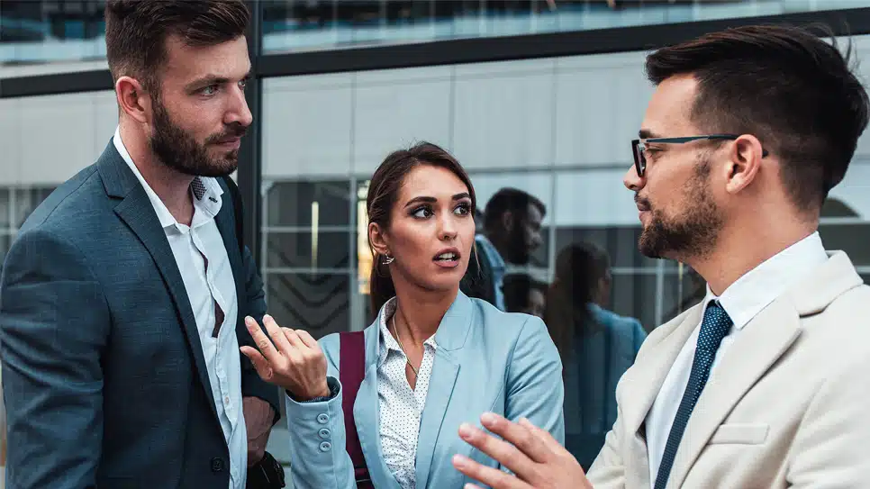three people interacting outside an office building