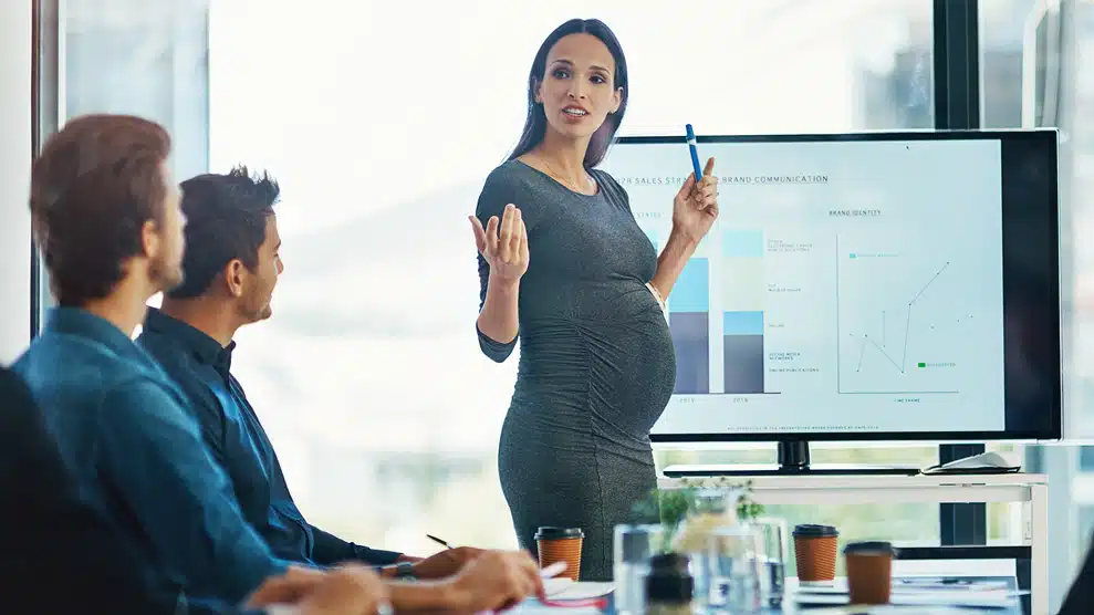 pregnant woman presenting a bar chart at work