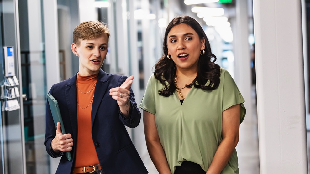 two coworkers conversing in a hallway