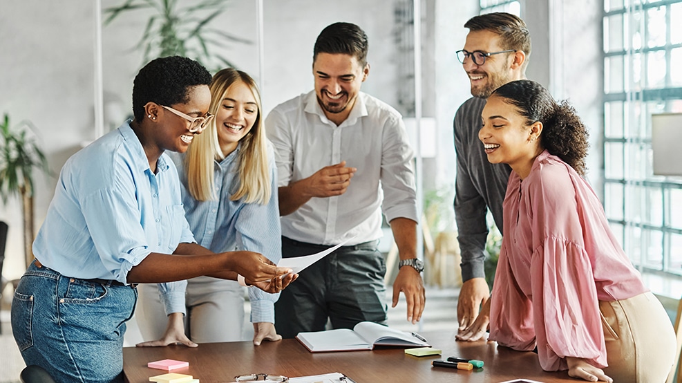 group of employees smiling around conference table