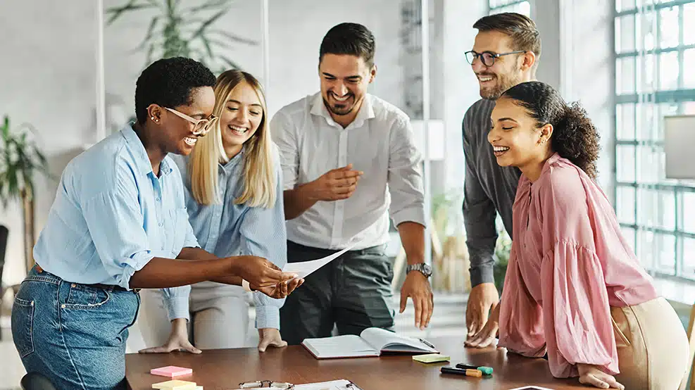 group of employees smiling around conference table
