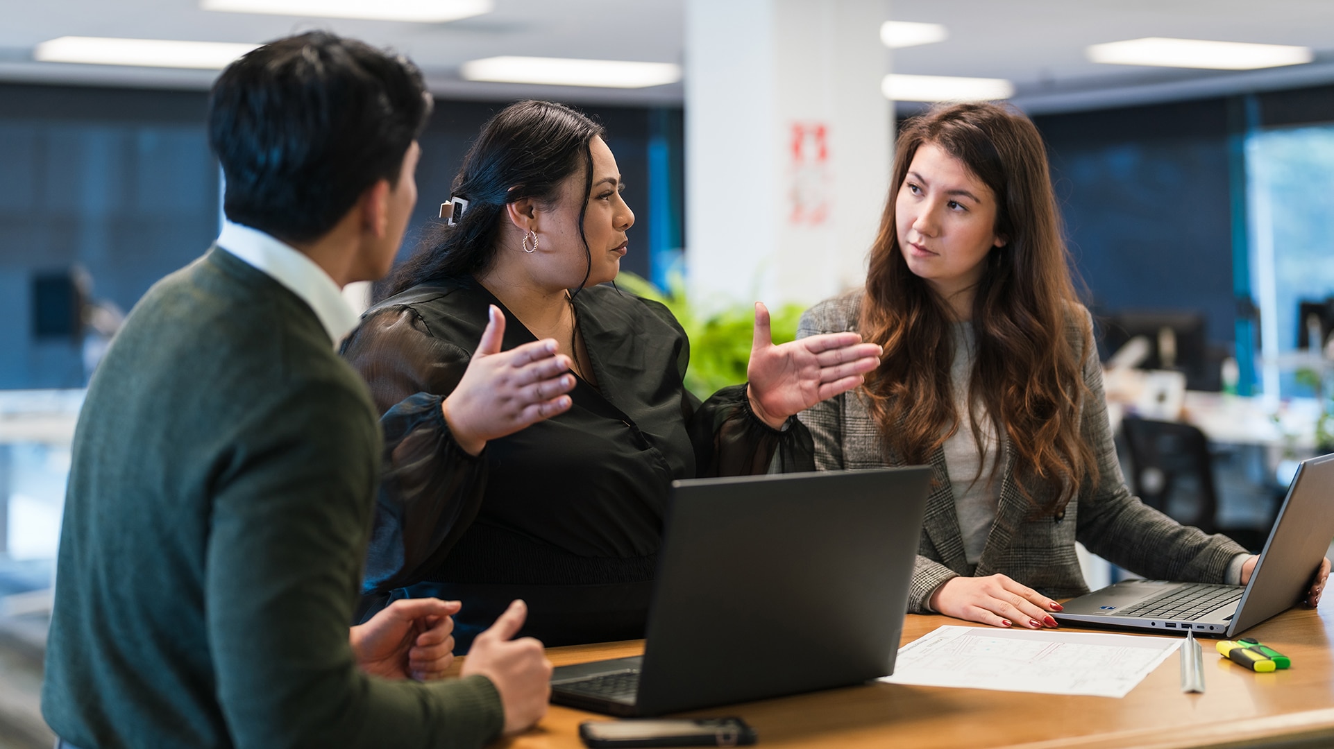 colleagues at a workspace with woman in middle gesturing