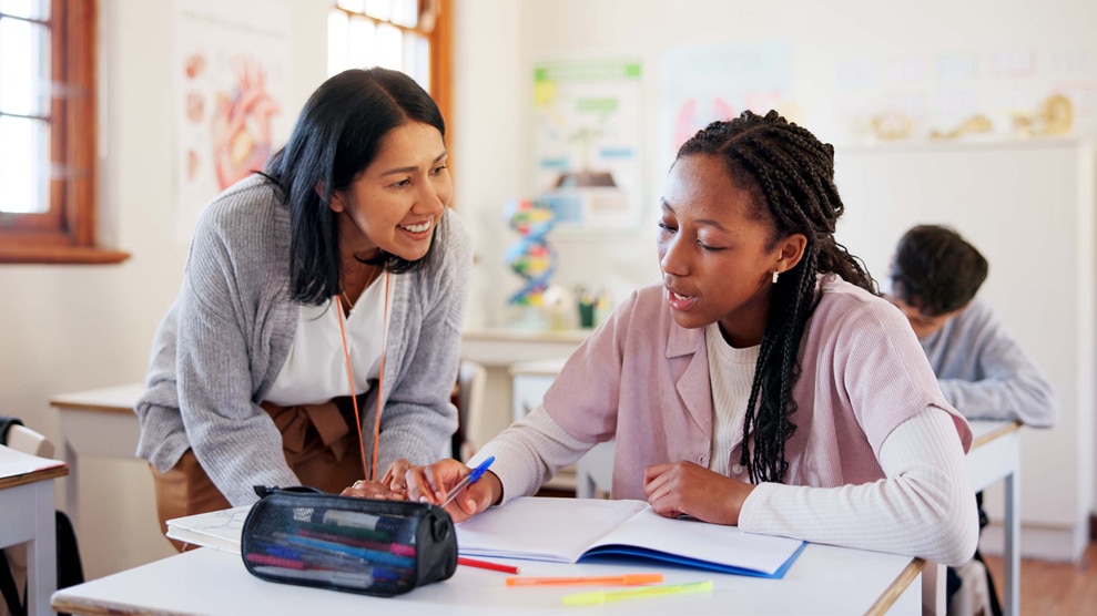 Teacher smiling over student's desk