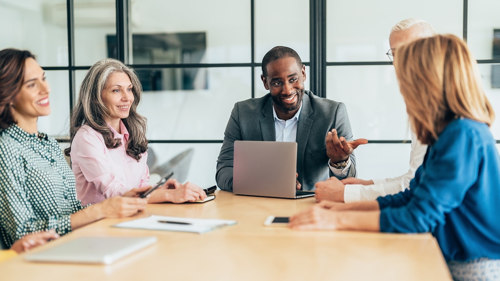 Group of colleagues at a meeting, with leader at the head of the table