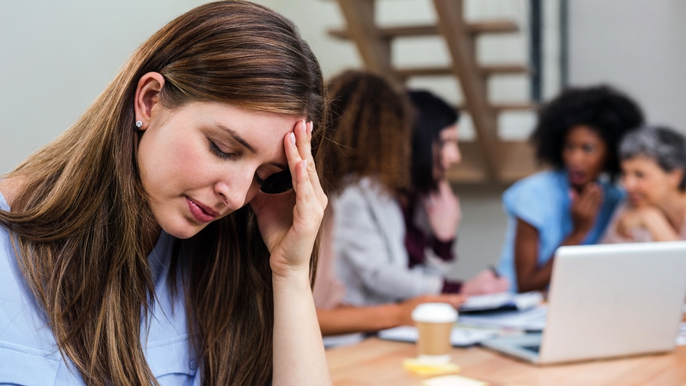 Woman with her head in her hands in front of colleagues