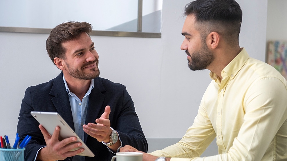 Man showing another person something on a tablet screen