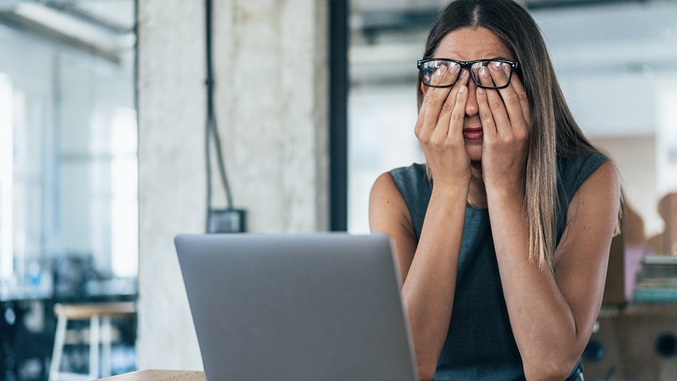 woman sitting at laptop head in hands, frustrated